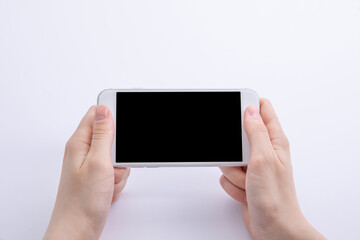 female hands holding new modern black smartphone isolated on white background, close view . High quality photo