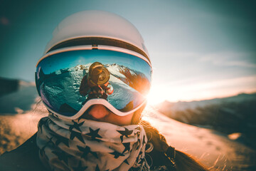 Young female skier on top on the mounatin during a golden sunset - extreme sports, travel, goal concept