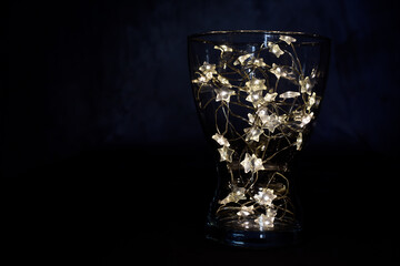 luces de navidad en copa de cristal y fondo negro