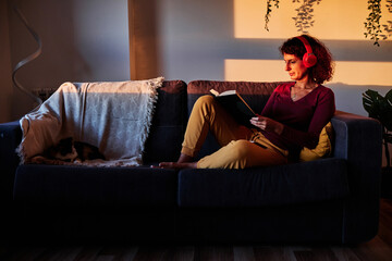 Obraz premium woman reading a book on couch during quarantine for coronavirus - stay at home concept