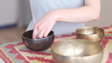 Woman playing on Tibetan singing bowl while sitting on yoga mat. Vintage tonned.