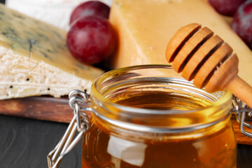 Cheese served with grapes and honey on grey surface