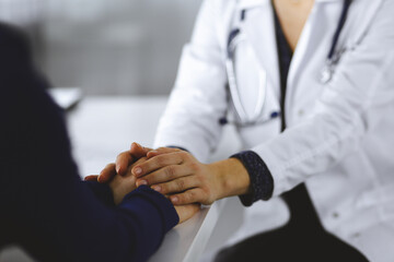 Fototapeta premium Unknown woman-doctor is reassuring her female patient, close-up. Physician is consulting and giving some advices to a woman. Concepts of medical ethics and trust. Empathy in medicine
