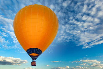 Naklejka premium Orange aerostat against the blue sky with white clouds, sharpness on the ball, used as a background