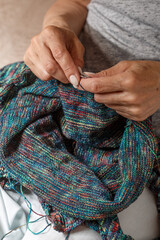 Close up of hands of unrecognizable woman knitting handmade clothes with spokes using  wool yarn. Concept of leisure activity.Knitting from yarn on  coarse spokes.