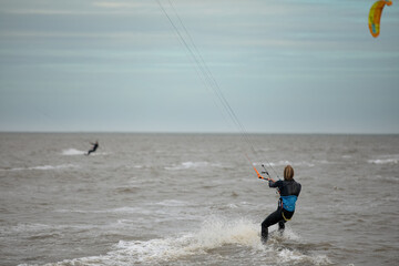 Man kitesurfing on the North Sea in a black wetsuit