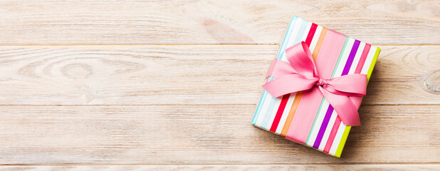paper gift box with colored ribbon on orange wood background. top view with copy space Christmas...