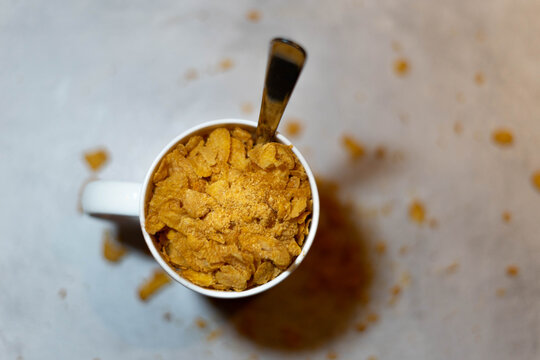 taza de cereales con cuchara y mesa gris con cereales caidos