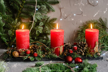 Christmas candles with fir-tree branches and baubles on wooden table