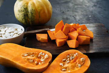 Cut pieces of raw pumpkin on wooden board on table