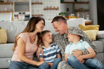 Happy soldier sitting on the floor with his family. Soldier and his wife enjoying at home with children