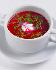 Ukrainian beetroot soup - borscht with sour cream served in a white bowl over white background.