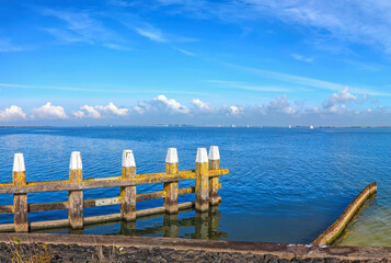 Fototapeta na wymiar Blue sea harbor pier panoramic landscape. Magnificent blue sky over calm expanse on a sunny day. Pastoral Dutch seascape. Netherlands