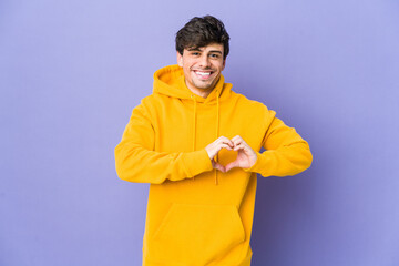 Young cool man smiling and showing a heart shape with hands.
