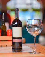 Wine glass and bottle of red wine on a wooden table over blurred background. Restaurant service, eating out concept.