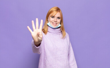 pretty woman  smiling and looking friendly, showing number four or fourth with hand forward,...