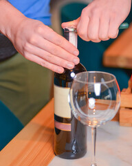 Wine glass and bottle of red wine on a wooden table over blurred background. Restaurant service, eating out concept.