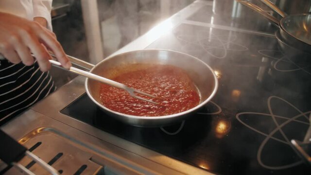 Chef cooking tasty pasta tomato sause on restaurant kitchen, traditional italian food, high kitchen cafe, man preparing dinner