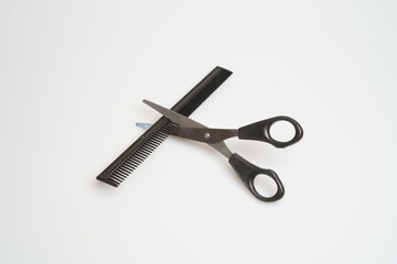 stainless steel scissors with black handle lie and comb on a light table