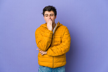 Young cool man yawning showing a tired gesture covering mouth with hand.