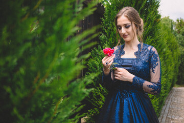 Beautiful girl in glamorous ultramarine dress holding a rose.