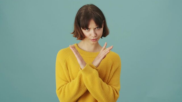 A serious woman is shaking head negatively standing isolated over a blue background in the studio