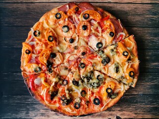 fresh delicious homemade pizza sliced into pieces on a dark table