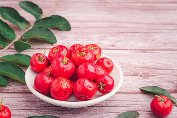 Ripe red cherries in a ceramic dish with leaves on a wooden table. Space for text. Sweet organic berries. Concept of healthy fruits