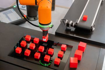 Pick and place robotic clamp arm manipulator moving red toy blocks at modern robot exhibition,...