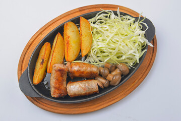 Grilled barbecue sausages and potatoes in the pan with mustard dip sauce. Fast food concept.