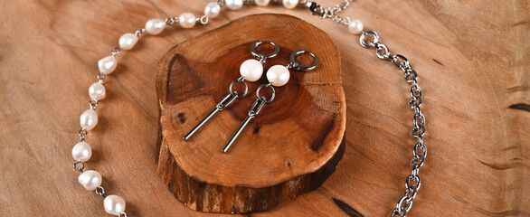 Fashionable silver earrings with pearls, necklace on wooden table. Feminine blog