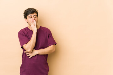 Young cool man yawning showing a tired gesture covering mouth with hand.