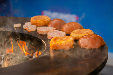 Process of preparing buns and fish cutlets for burgers on brazier with hot flame at summer local food market - close up view. Outdoor cooking, gastronomy, cookery, street food concept