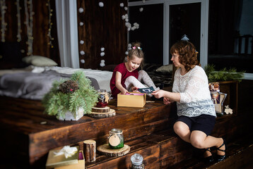 Christmas, New Years holidays.  A woman with a little girl open gifts.
