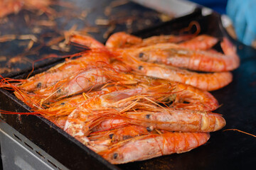 Close up: process of cooking fresh red langoustine shrimps, prawns on grill at summer local food market. Outdoor cooking, barbecue, gastronomy, seafood, cookery, street food concept