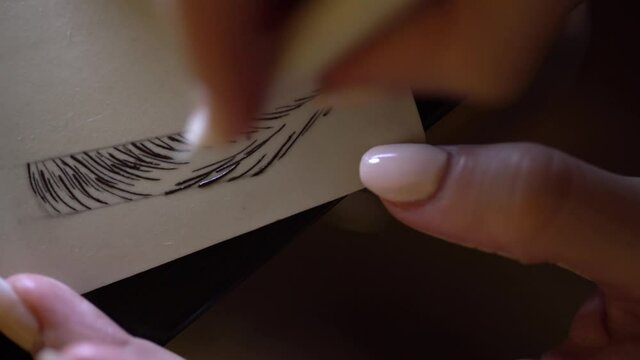 Girl practices permanent makeup microblading on fake skin.