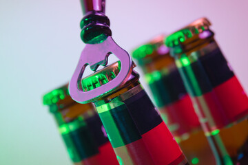 close up of a bottle opener and a cold beer in a party and fun atmosphere and lights
