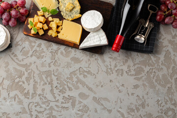 Composition with wine bottle and cheese assortment on grey background