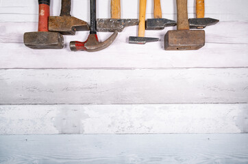 set of different types of old hammers in line at the top of a space on a wooden background. top view with space for text