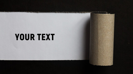 A torn strip of a sheet of black paper is rolled up. Place for your text. Copy space