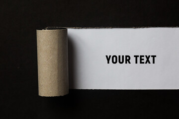 A torn strip of a sheet of black paper is rolled up. Place for your text. Copy space.