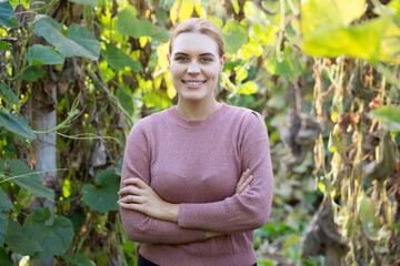 Portrait of woman farmer posing on background of organic zucchini plantation