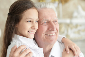Obraz na płótnie Canvas Portrait of happy elderly man with cute granddaughter