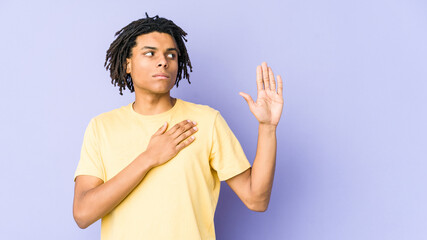 Young african american rasta man taking an oath, putting hand on chest.