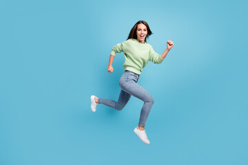 Fototapeta na wymiar Full length body size side profile photo of laughing young girl running fast hurrying up jumping high smiling happily isolated on bright blue color background