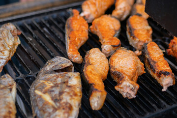 Process of cooking salmon steaks and mackerel fish on grill over charcoals at summer local food market - close up. Outdoor cooking, barbecue, gastronomy, seafood, cookery, street food concept