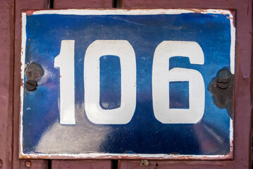 Weathered grunge square metal enameled plate of number of street address with number 106