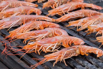 Process of cooking fresh red langoustine shrimps, prawns on grill at summer local food market - close up. Outdoor cooking, barbecue, gastronomy, seafood, cookery, street food concept