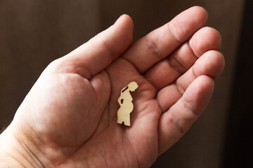 Silhouette figure of a pregnant woman lies on a man's hand