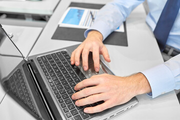 business, people and technology concept - close up of businessman with laptop computer at office